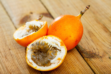 Closeup of whole and halved ripe passiflora fruits on wooden background