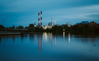 Pipes of CHP near the lake. Evening cityscape