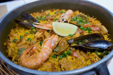 The famous traditional fish dish of spanish food and catalan cuisine - seafood paella with shrimps, mussels, fish, rice, lemon and herbs