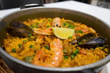 The famous traditional fish dish of spanish food and catalan cuisine - seafood paella with shrimps, mussels, fish, rice, lemon and herbs