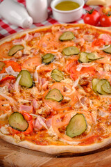 Pizza Bavaria. Rustic pizza with ham, tomato sauce, pepper, pickled cucumbers, onion, chicken meat, cheese in italian restaurant background, top view. Pizza from wooden oven. Close up