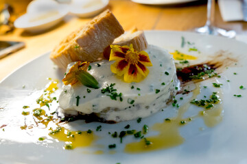 A traditional appetizer, snack or tapas from Spanish cuisine and Catalan food - baked eggplant served with white cheese (sour cream) and crispy toasted bread in the restaurant of Barcelona, Spain