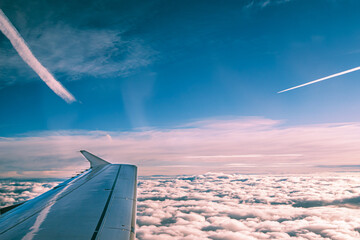 Airplane wing from window flying above the clouds, aerial view of cloud and sky. Travel concept.