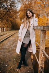 beautiful long-haired woman walks through the autumn streets. Railway, autumn, woman in a coat.