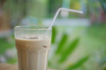 Close up of iced coffee milk with green garden background