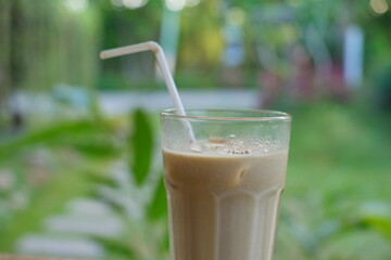 Close up of iced coffee milk with green garden background