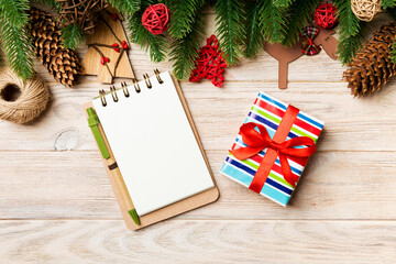 Fototapeta na wymiar Top view of gift, notebook, Christmas toys, decorations and fir tree branches on wooden background. New Year holiday concept