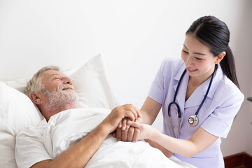 Nurse cares for elderly man lying in bed