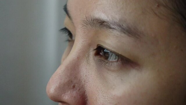 Mixed race Southeast Asian woman close-up eyes tired looking at computer monitor screen