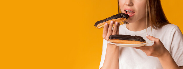 Unrecognizable young girl eating tasty eclairs with chocolate cream