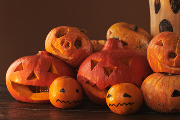 Group of spooky pumpkins, gourds and tangerines carved and painted for Halloween party decoration...