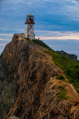 Fototapeta na wymiar Rudny lighthouse at Cape Briner in the village of Smychka (Rudnaya Pristan), Primorsky Territory. The beautiful Rudny lighthouse stands on a sheer cliff against the backdrop of a bright dawn