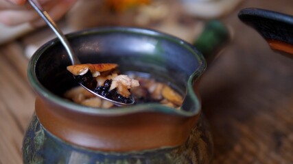 Close up of stirring hot tea in a traditional tea pot. Flowers and pieces of dry fruit on teaspoon. 