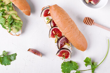 Sandwiches with figs and avocado on the white table. Two sandwiches with different toppings