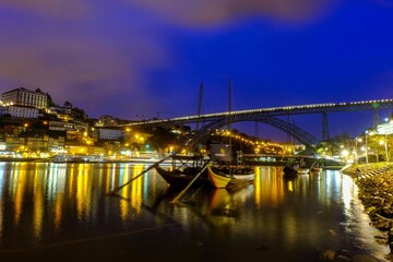 Fototapeta na wymiar Beautiful Porto cityscape at night with boats and bridge over the river