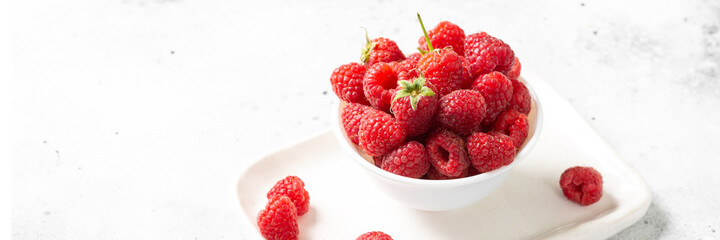 Berries. Raspberries in a white bowl on a light table. Fresh raspberries in a plate. Healthy diet. Banner
