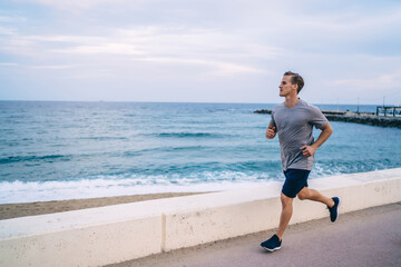 Serious handsome 20s hipster guy jogging in morning on active healthy lifestyle reaching fitness goals, caucasian sportsman running on cardio workout training body and physical body strength