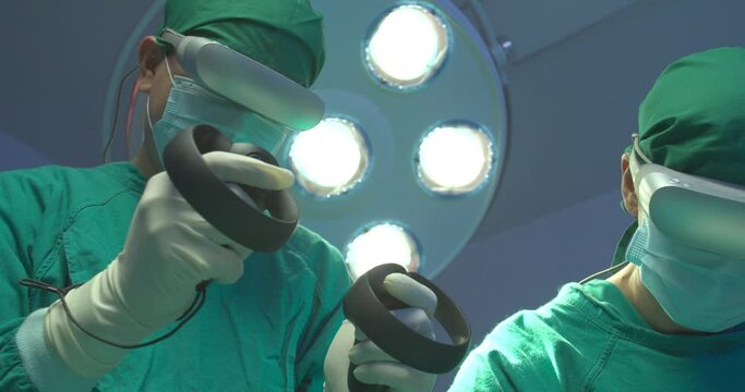 Team of surgeons wearing augmented reality headsets and using joysticks performing operation on a patient in operating theater at the hospital. Teamwork, Healthcare and medical technology concept.
