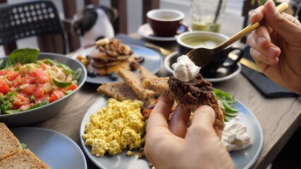 Hands spreading dips on piece of brown bread.Healthy balanced vegan brunch.