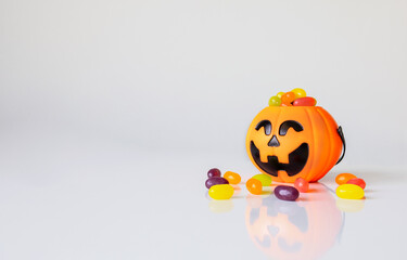 colorful candy in pumpkins bucket on white table background. halloween concept.