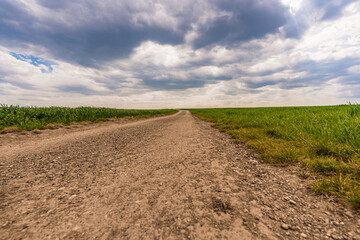 Strasse mit Feld und bewölktem Himmel