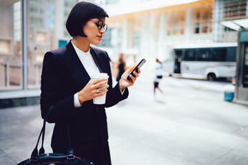 Elegant businesswoman browsing smartphone on street