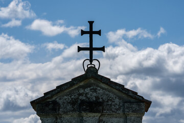 Close Up eines Daches mit Kreuz mit bewölktem Himmel im Hintergrund