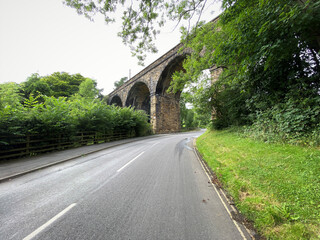Old stone railway viaduct, with trees and bushes on, Station Road, Esholt, Bradford, UK