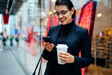 Executive trendy woman text messaging on phone having coffee