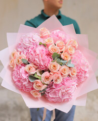 Man with bunch of pink hydrangea and roses. Young man holding a big bouquet of pink  flowers in Women's day. Fresh cut flowers.