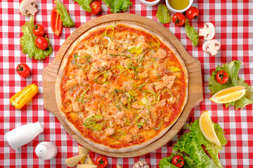 Rustic pizza with atlantic salmon, cheese, tomato, leek and tomatoes sauce in italian restaurant background, top view. Classic Italy food. Pizza from wooden oven. Close up