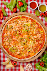 Rustic pizza with atlantic salmon, cheese, tomato, leek and tomatoes sauce in italian restaurant background, top view. Classic Italy food. Pizza from wooden oven. Close up