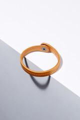 Subject shot of ginger bracelet made as leather strap with middle stitch and steel snap fastener....