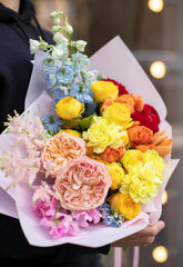 Colorful flowers assorted bouquet in bright paper. Bouquet of beautiful flowers in hands. Colorful flowers bouquet wrapped in paper