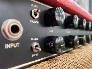 Close-up modern black volume knob of the boutique clean guitar amplifier with blurred black control...