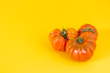 View of beautiful red heirloom tomatoes on yellow background