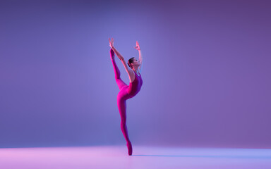 Freedom. Young and graceful ballet dancer isolated on purple studio background in neon light. Art,...