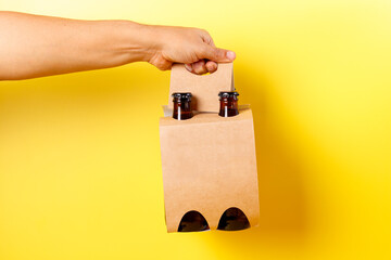 Hand holding a four pack beer presentation with yellow background