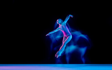 Fototapeta na wymiar Flying bird. Young and graceful ballet dancer on black studio background in neon mixed light. Art, motion, action, flexibility, inspiration concept. Flexible caucasian ballet dancer, weightless jumps.