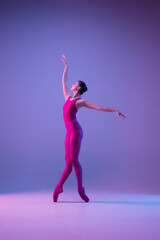 Dynamic. Young and graceful ballet dancer isolated on purple studio background in neon light. Art, motion, action, flexibility, inspiration concept. Flexible caucasian ballet dancer, weightless jumps.