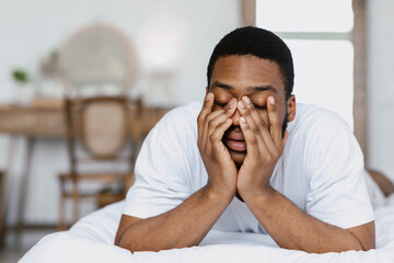 Fototapeta na wymiar Sleepy African Man Rubbing Eyes Waking Up In Bed Indoors