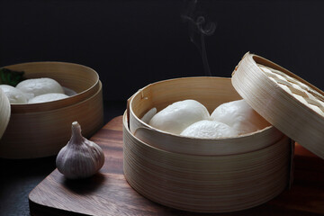 pork and egg creamy steam buns are in the dim sum basket and served on the black wooden table in Chinese Cantonese restaurant with a cup of milk tea during tea time