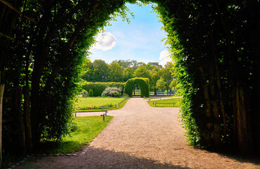 View through the green pergola into the palace gardens of Schwerin with a blue sky.