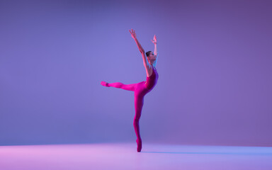 Beautiful. Young and graceful ballet dancer isolated on purple studio background in neon light. Art, motion, action, flexibility, inspiration concept. Flexible caucasian ballet dancer, weightless - obrazy, fototapety, plakaty