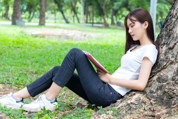 Asian woman relax by sitting happily reading a book in the park.  Concept happy living of the new generation