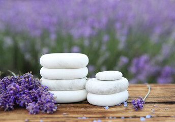 Spa stones, fresh lavender flowers and bath salt on wooden table outdoors, closeup