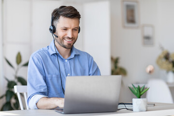 Call center operator at work. Male manager wearing headset and using laptop - obrazy, fototapety, plakaty