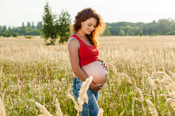 A pregnant woman is posing in the wheat field