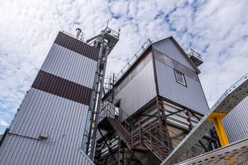 Modern Granary elevator. Silver silos on agro-processing and manufacturing plant for processing drying cleaning and storage of agricultural products, flour, cereals and grain.