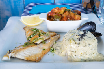Fresh catch of the day as a delicios dish of French cuisine - grilled mediterranean fish fillet served with boiled risotto, vegetable ratatouille and mussels in the restaurant of Gruissan, France
